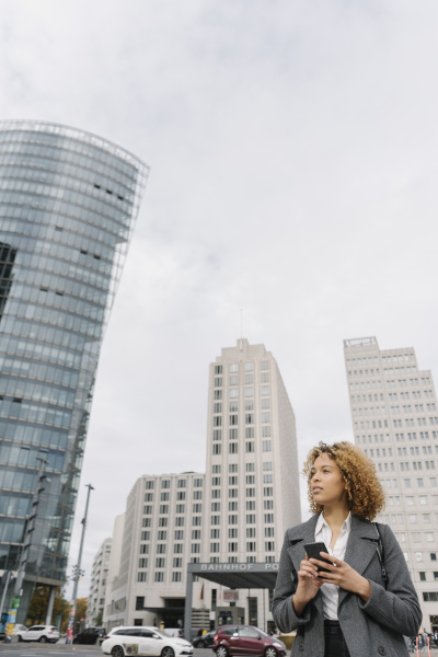 woman holding smartphone with office buildings