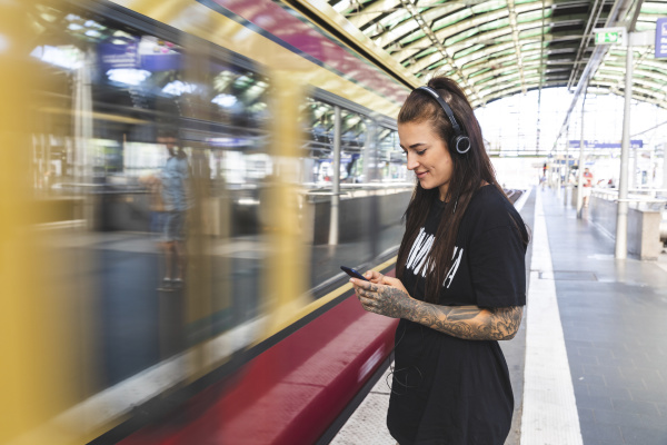 tattooed young woman with headphones standing