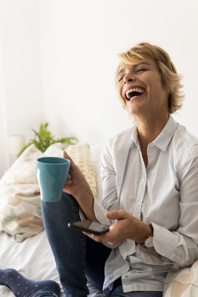 laughing mature woman sitting on bed