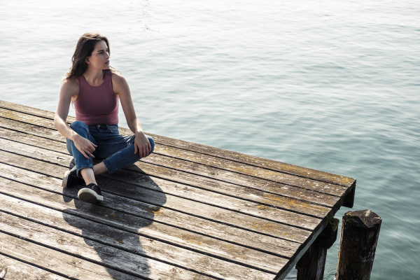 young woman sitting on jetty looking