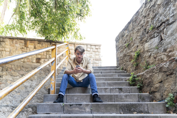 man sitting on outdoor stairs using