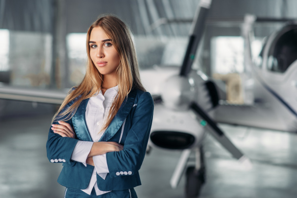 stewardess-against-propeller-plane-in-hangar-stock-photo-28093889