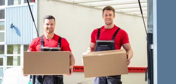 happy male movers holding cardboard boxes