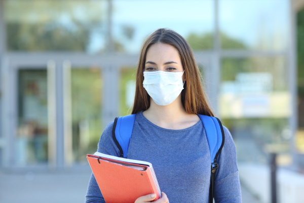student wearing a mask walking in
