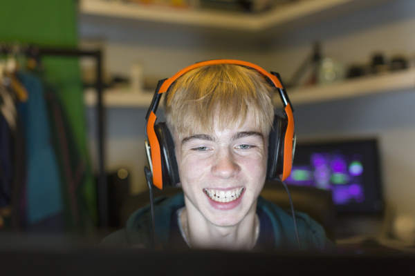 happy teenage boy with headset playing