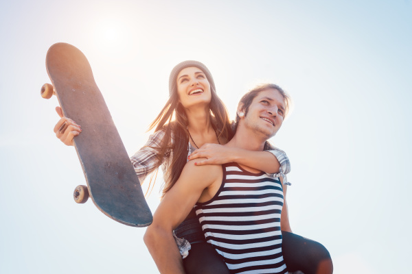man carrying his girlfriend with skateboard