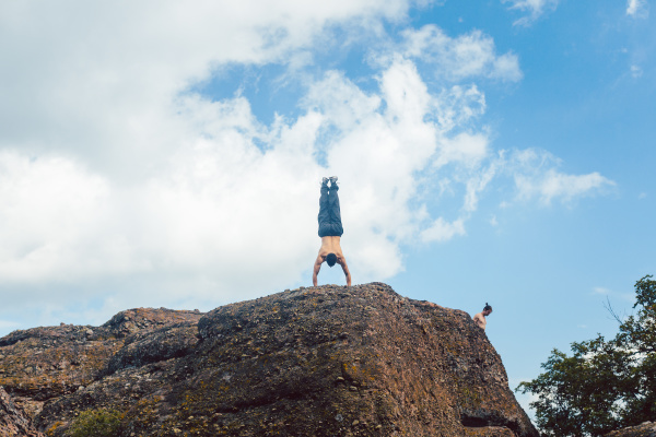 acrobat doing handstand on a cliff