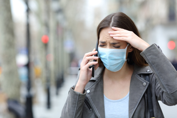 worried woman with protective mask calling