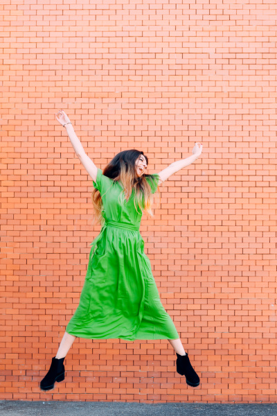 woman in a green dress jumping