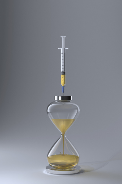 studio shot of hourglass and syringe