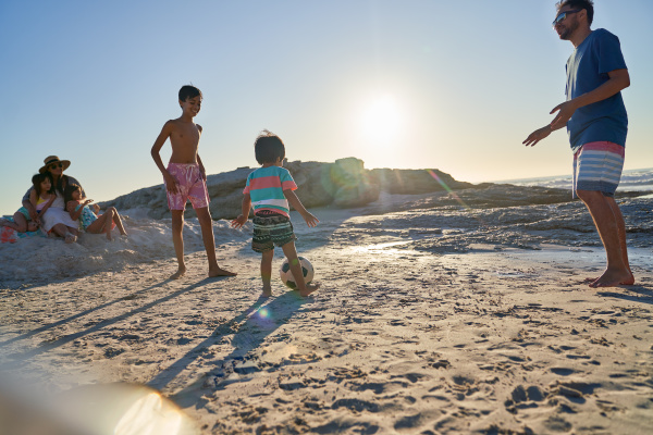 family playing soccer on sunny beach