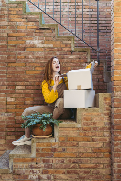 carefree young woman opening box while