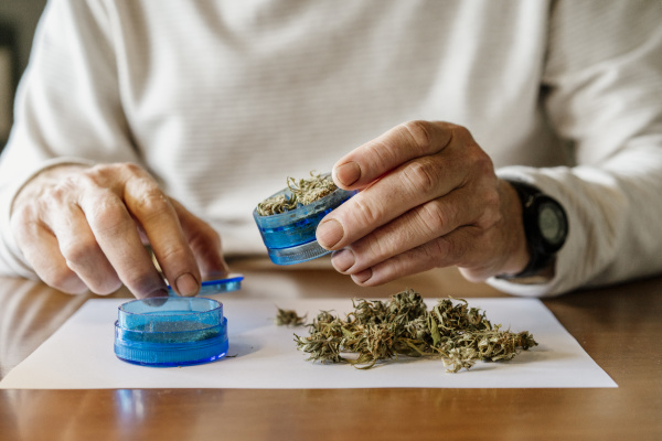midsection of senior man grinding weed