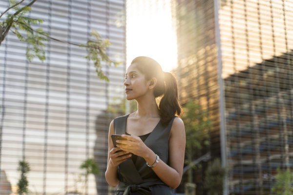 thoughtful businesswoman holding smart phone while