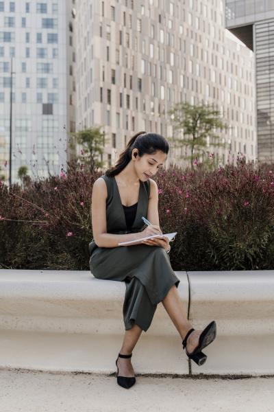 businesswoman writing in note pad while