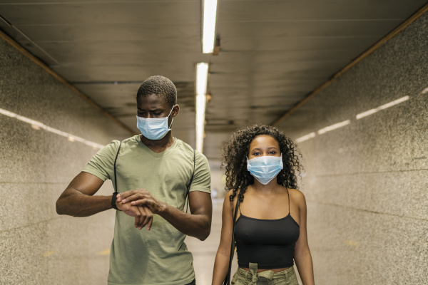 couple wearing masks underground walkway at