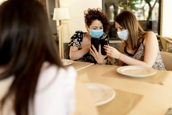 women wearing masks while sharing digital