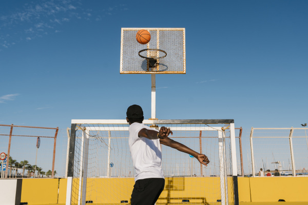 young man playing basket against blue