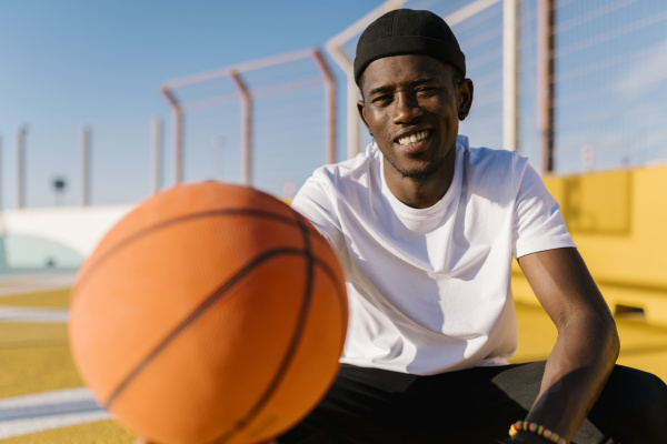 smiling young man holding basketball while