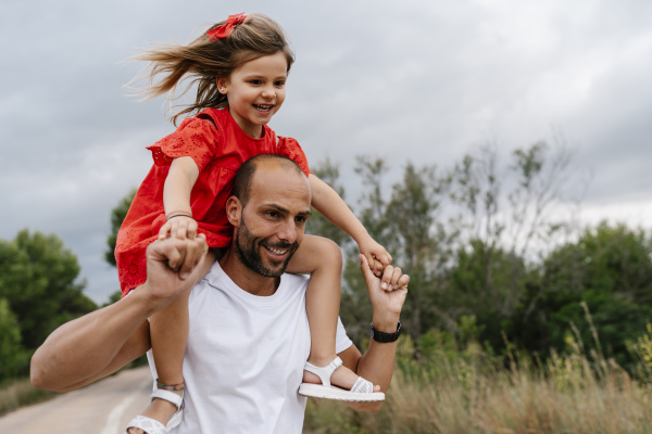 happy man carrying daughter on shoulders