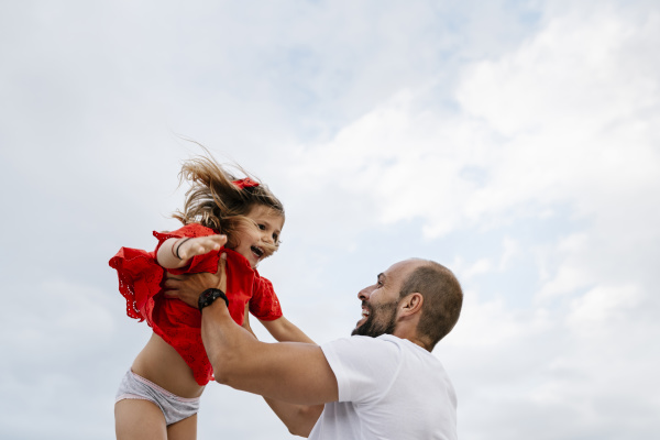 cheerful father holding aloft daughter against