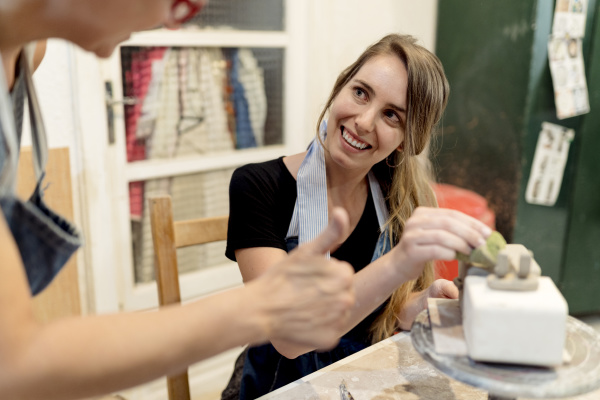 young woman showing ceramics to coworker