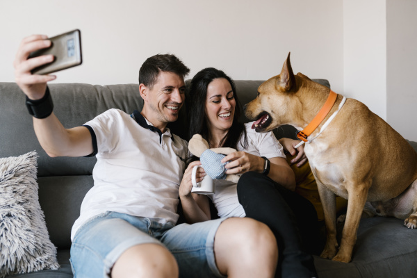 smiling couple taking selfie with dog