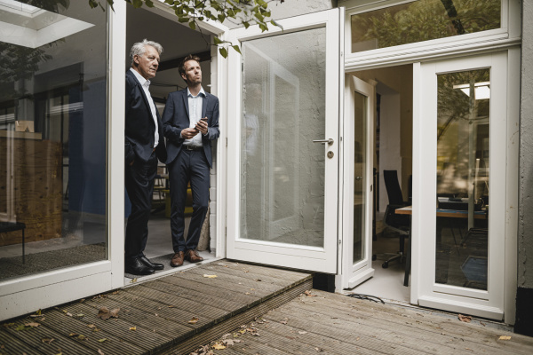 two businessmen leaning in office door