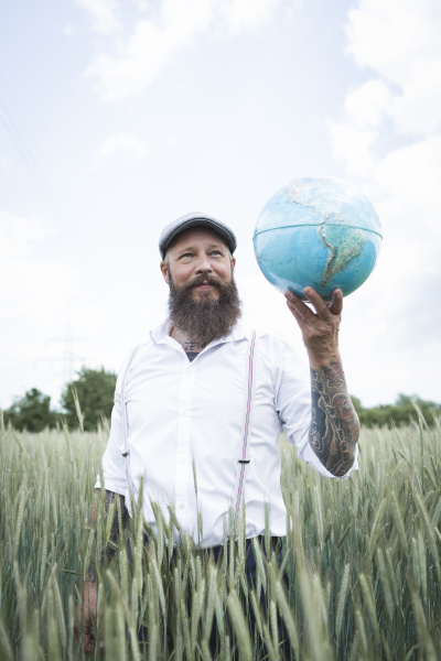 bearded man holding globe looking away