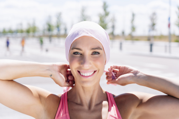 happy sporty woman tying headscarf on