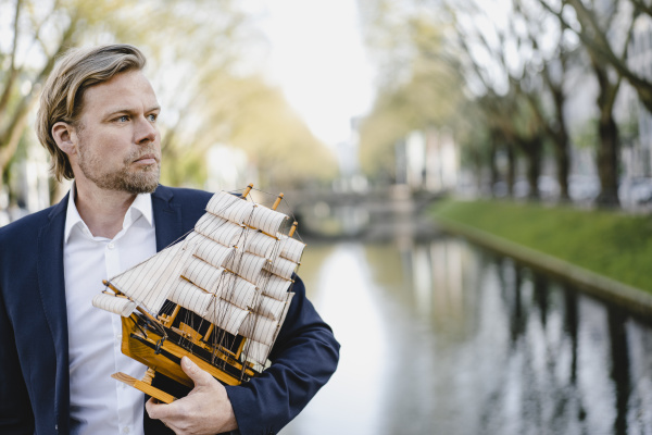 businessman holding model ship at a