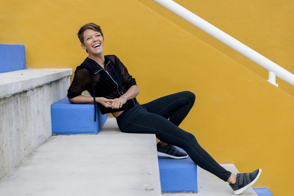 laughing athletic woman sitting on stairs