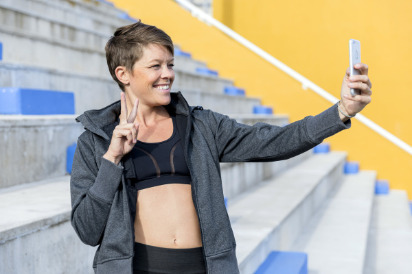 athletic woman using smartphone and taking