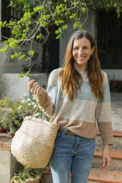 smiling woman carrying wicker basket while