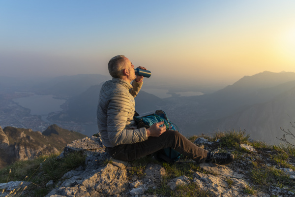 hiker drinking on viewpoint at sunset