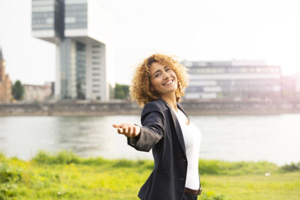 smiling businesswoman with arm outstretched standing