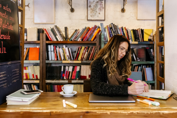 woman writing in notebook in coffee