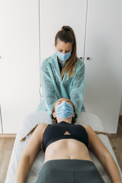 doctor wearing face mask examining sportswoman