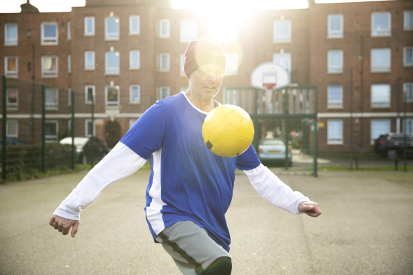 mature man playing with football on