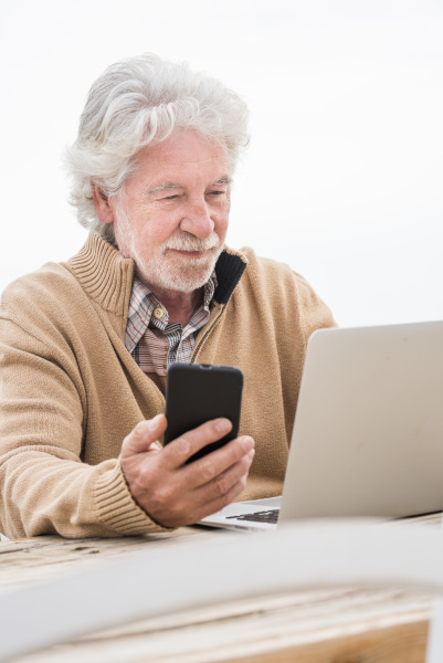 senior man holding smart phone while