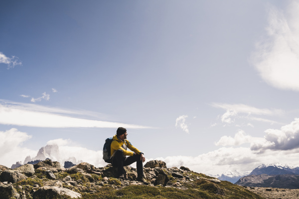 male hiker sitting on mountain against