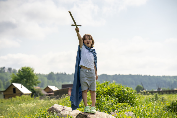 playful boy wearing cape holding toy