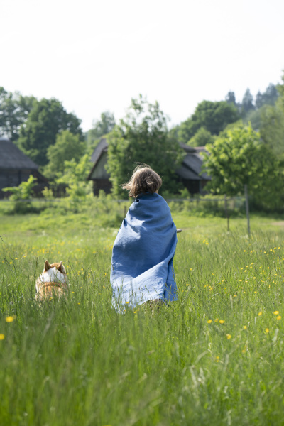 boy wearing cape standing with dog
