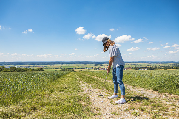 young woman playing golf at countryside