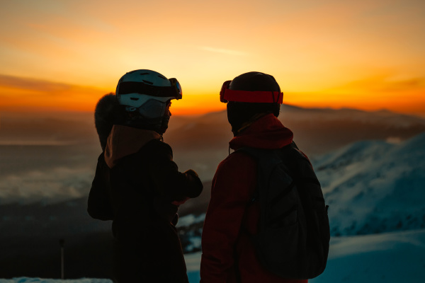 silhouette of two people wearing ski