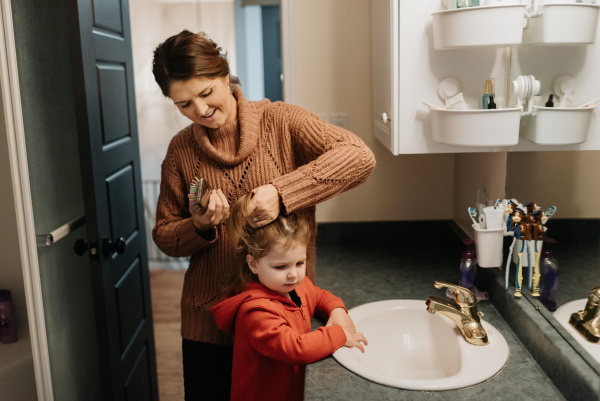 a woman brushing her daughters hair