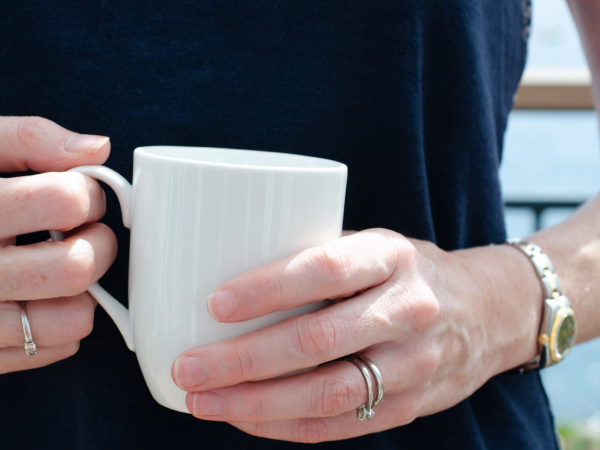 womans hands holding a white mug