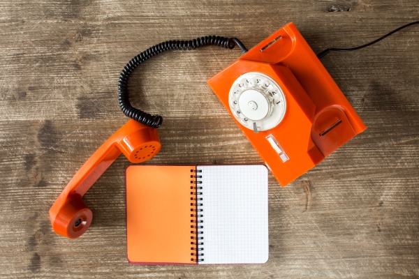 old orange telephone and blank notebook