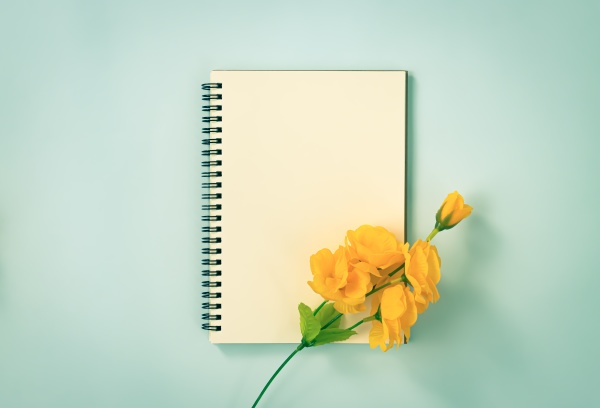 spiral notebook and orange flowers at