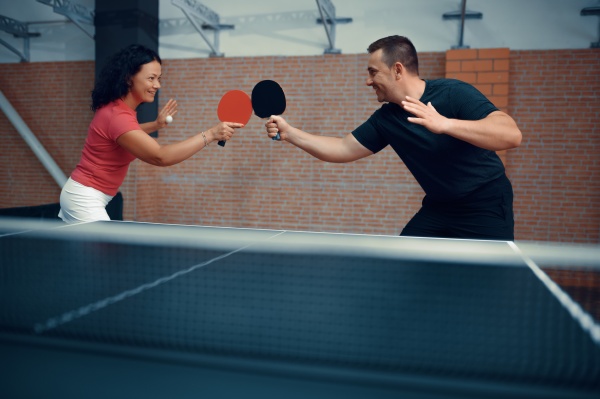 man and woman play table tennis